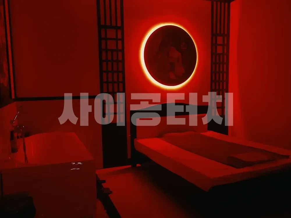 붉은 조명과 원형 거울이 있는 마사지 룸