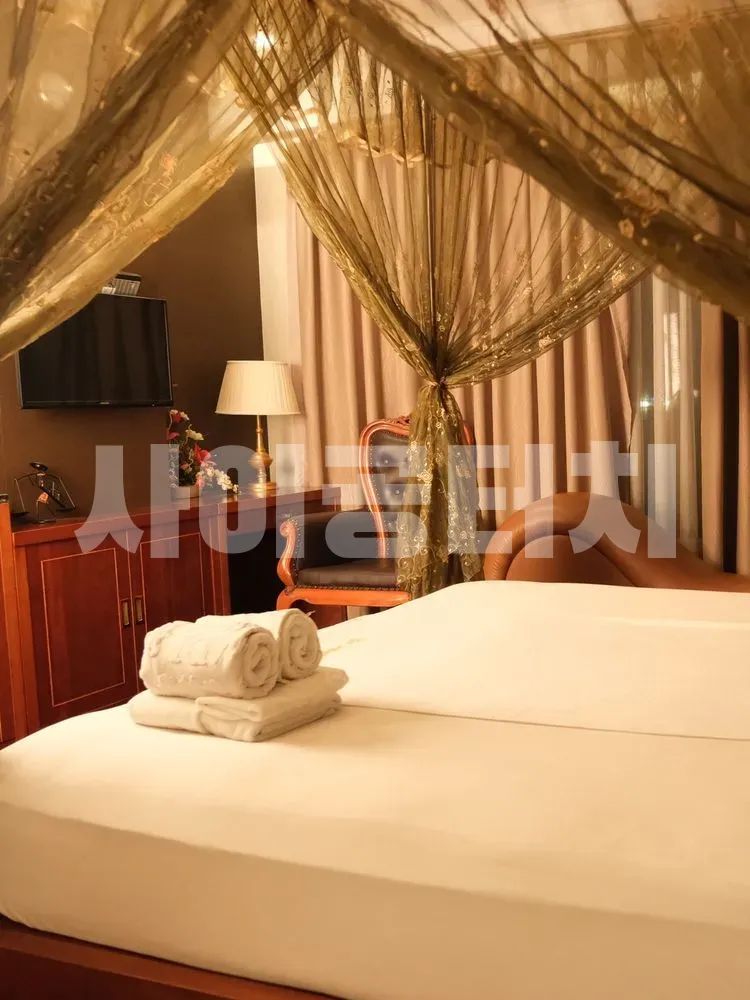 짙은 녹색 캐노피와 수건이 놓인 침대