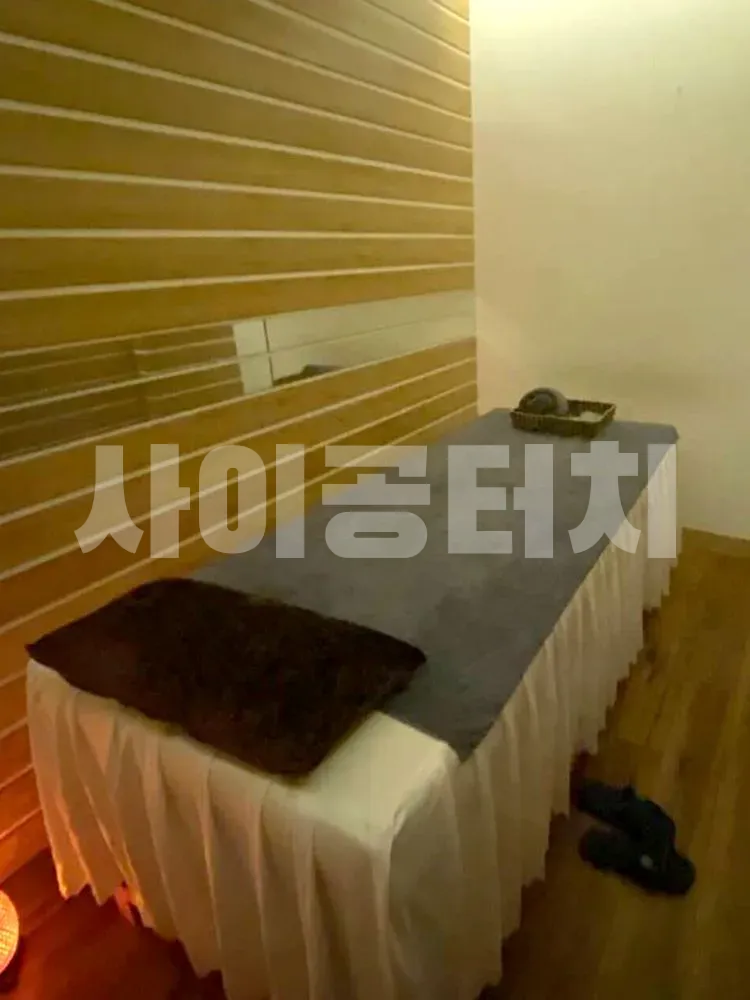 나무 벽으로 꾸며진 방에 놓인 마사지 베드