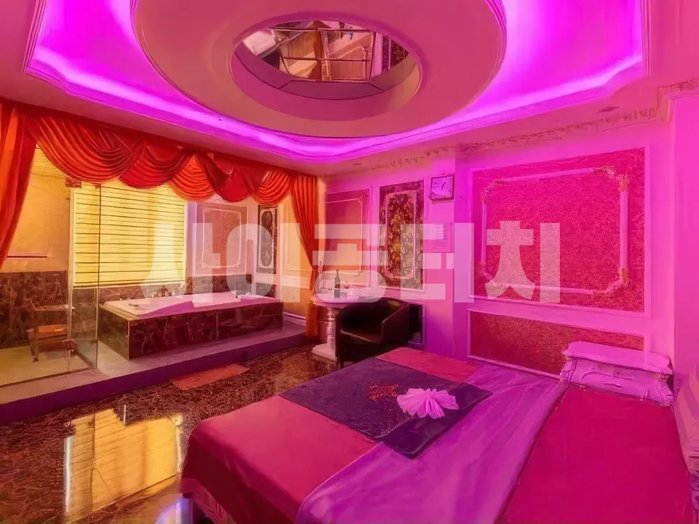분홍색 조명과 원형 욕조가 있는 마사지 룸